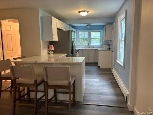 Kitchen island with a light-toned quartz countertop, and multiple windows Kitchen island with a light-toned quartz countertop, and multiple windows