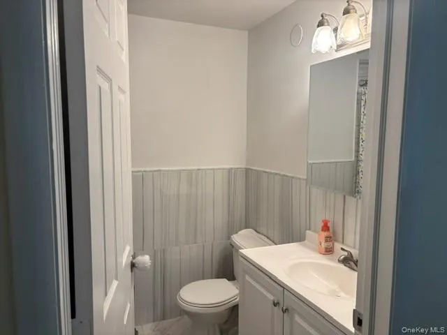 Vanity with integrated sink, white cabinetry, wall-mounted mirror, and decorative light fixture Vanity with integrated sink, white cabinetry, wall-mounted mirror, and decorative light fixture