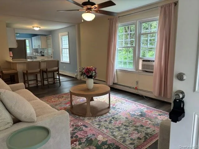 Open-concept living space featuring laminate flooring, a ceiling fan with integrated lighting, and a kitchen pass-through with a breakfast bar Open-concept living space featuring laminate flooring, a ceiling fan with integrated lighting, and a kitchen pass-through with a breakfast bar