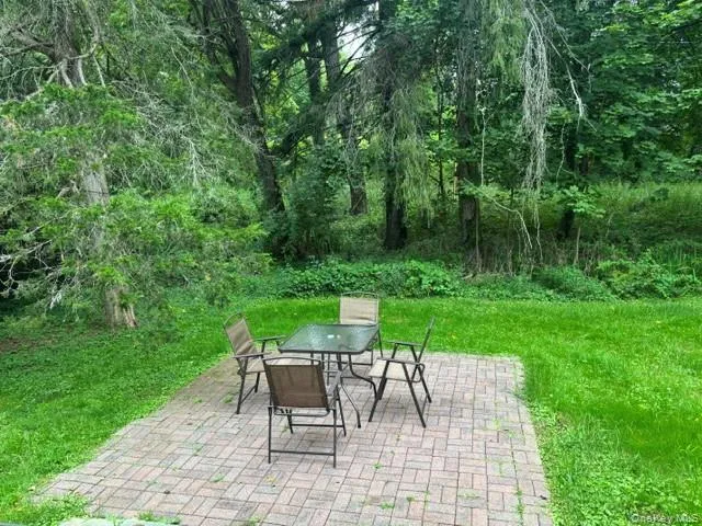 Paved patio area, surrounded by green grass, with mature trees in the background Paved patio area, surrounded by green grass, with mature trees in the background