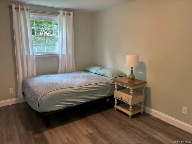 Laminate flooring with white trim, a single window, and neutral wall tones Laminate flooring with white trim, a single window, and neutral wall tones