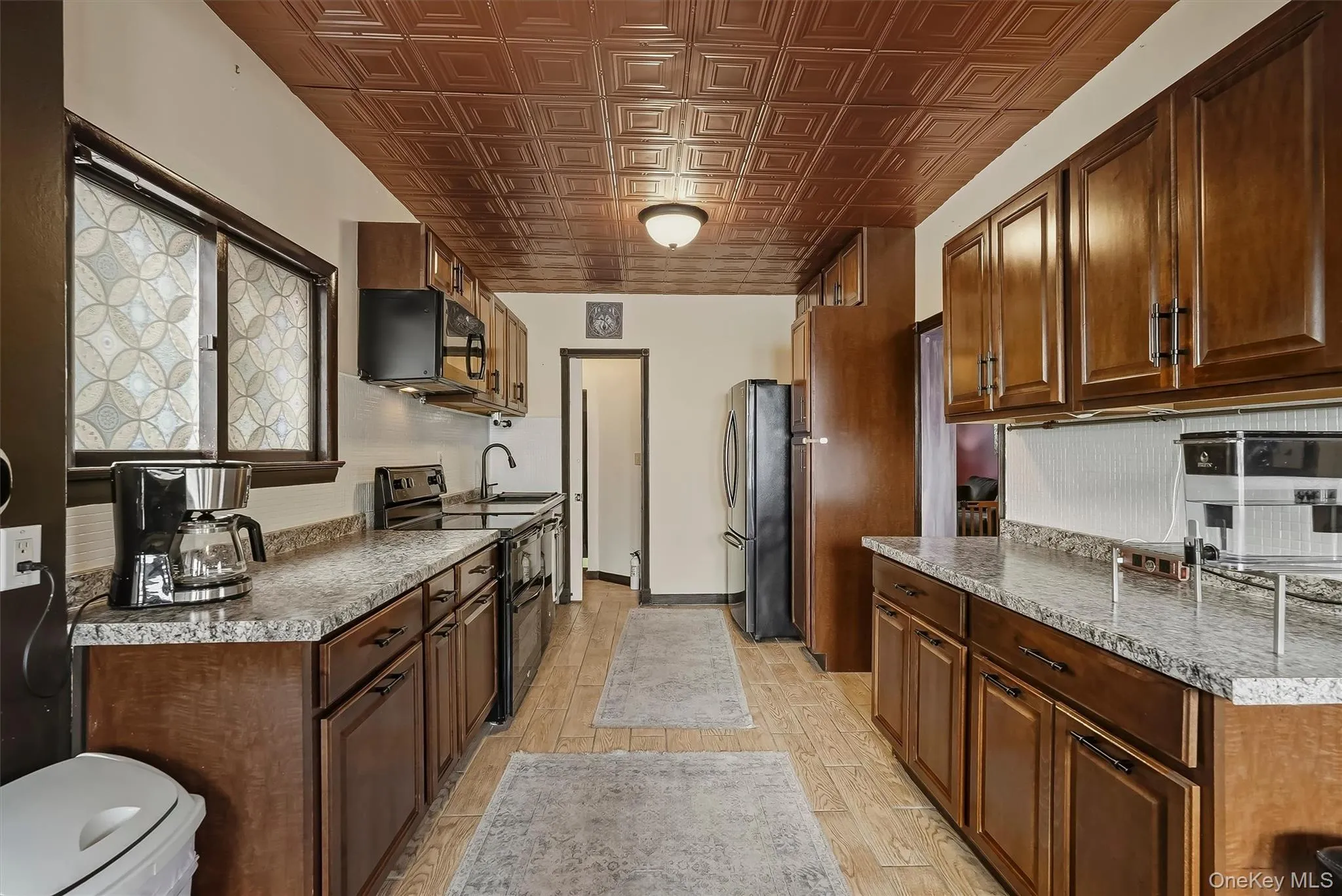 The kitchen is accented with a faux tin ceiling and custom tile flooring. The kitchen is accented with a faux tin ceiling and custom tile flooring.