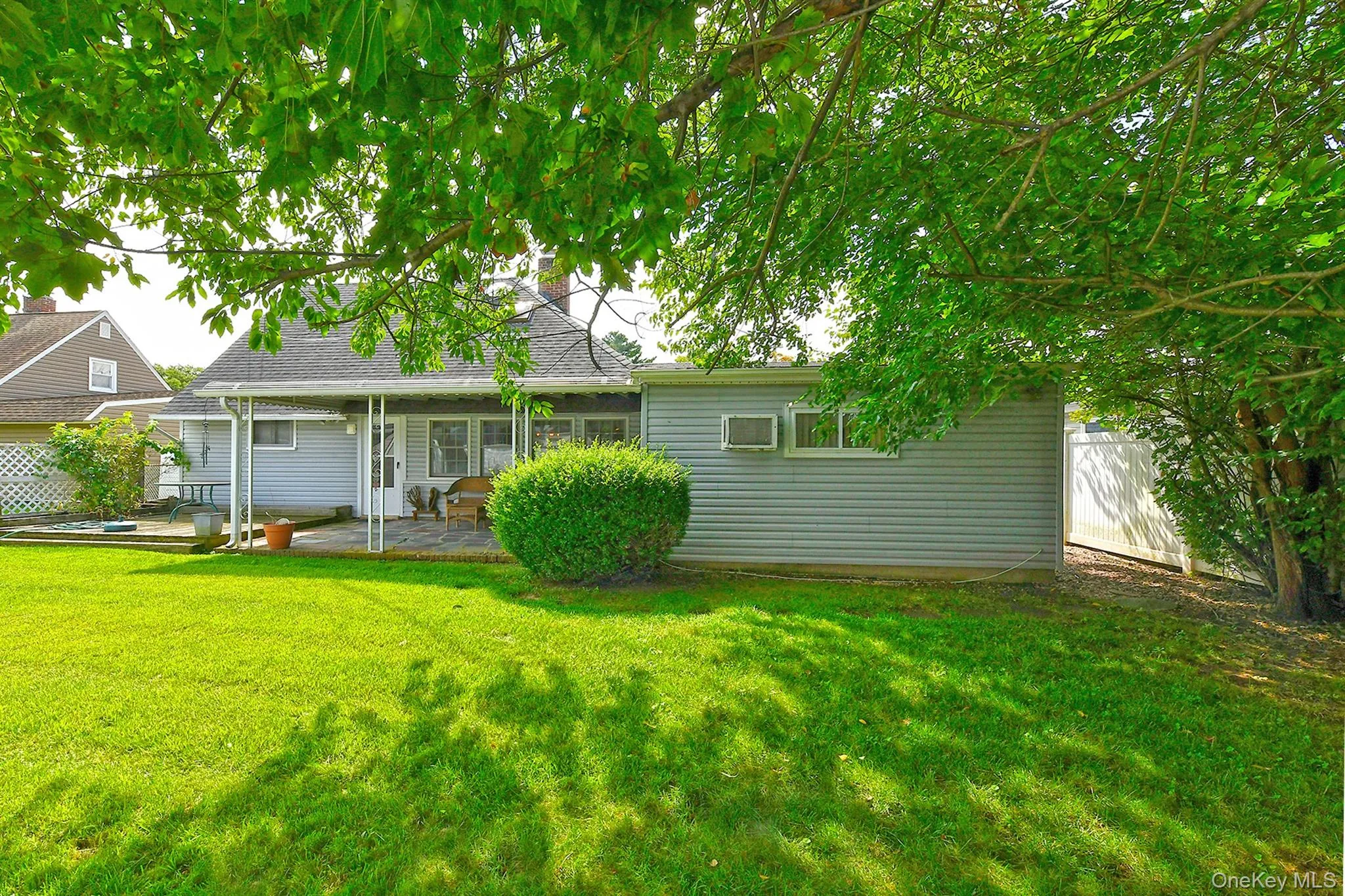 Expansive green lawn, covered patio, stone paver patio surface, and mature perimeter landscaping Expansive green lawn, covered patio, stone paver patio surface, and mature perimeter landscaping