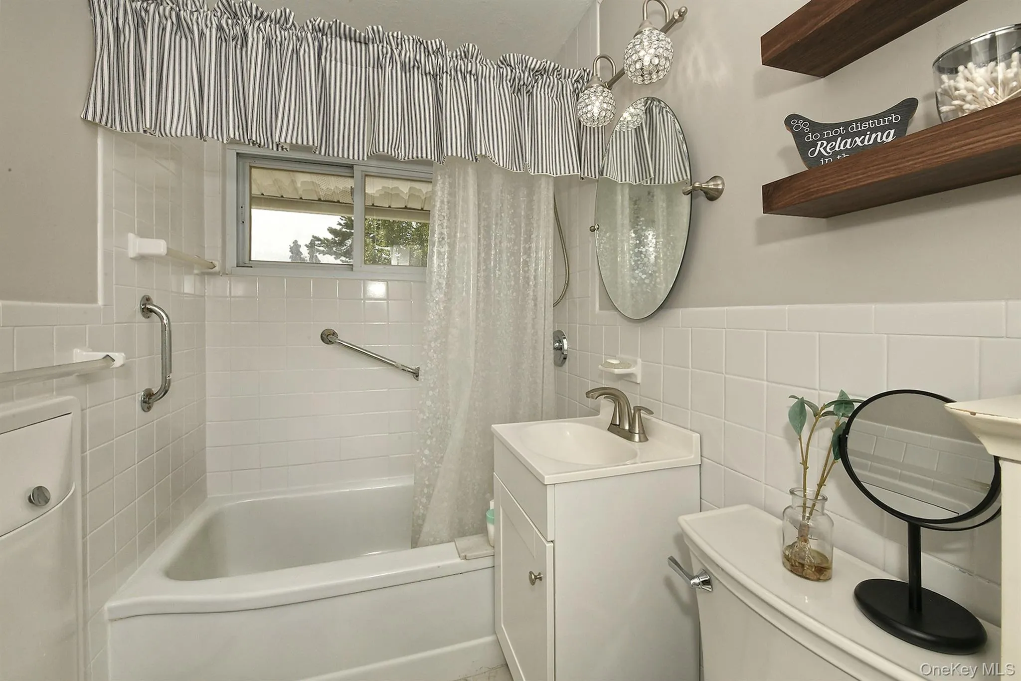 White ceramic tile wainscoting and, built-in bathtub, and a window with privacy glass White ceramic tile wainscoting and, built-in bathtub, and a window with privacy glass