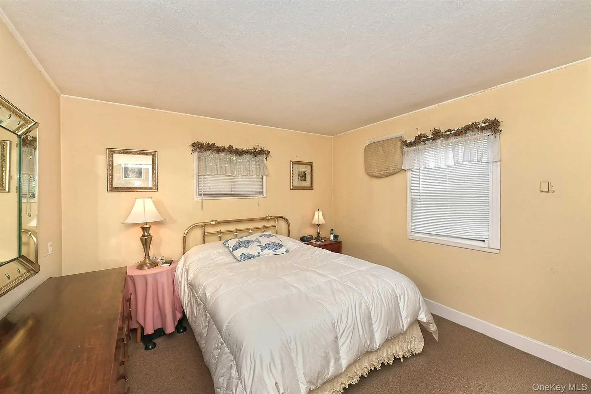 Masterbedroom: window with blinds and valence, wall-mounted air conditioning unit, and textured carpeting Masterbedroom: window with blinds and valence, wall-mounted air conditioning unit, and textured carpeting