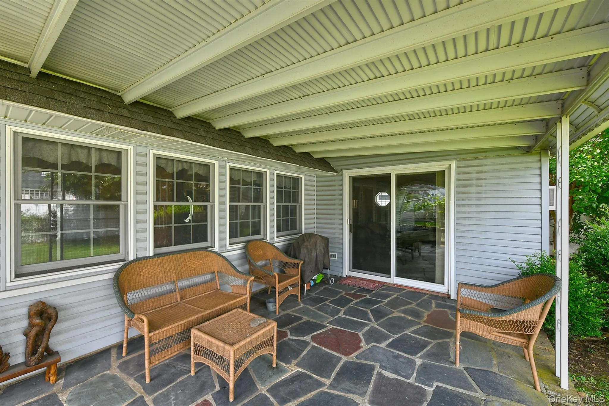 Covered patio featuring a stone-look tile floor, sliding glass door, and multiple windows Covered patio featuring a stone-look tile floor, sliding glass door, and multiple windows