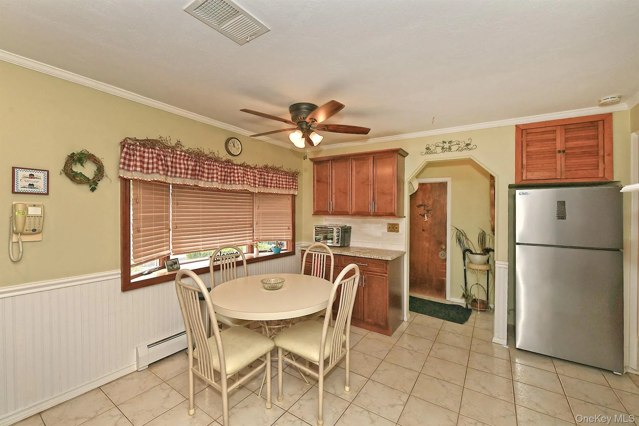 Tile flooring, wood-finish cabinetry, stainless steel refrigerator, beadboard wainscoting, and crown molding Tile flooring, wood-finish cabinetry, stainless steel refrigerator, beadboard wainscoting, and crown molding