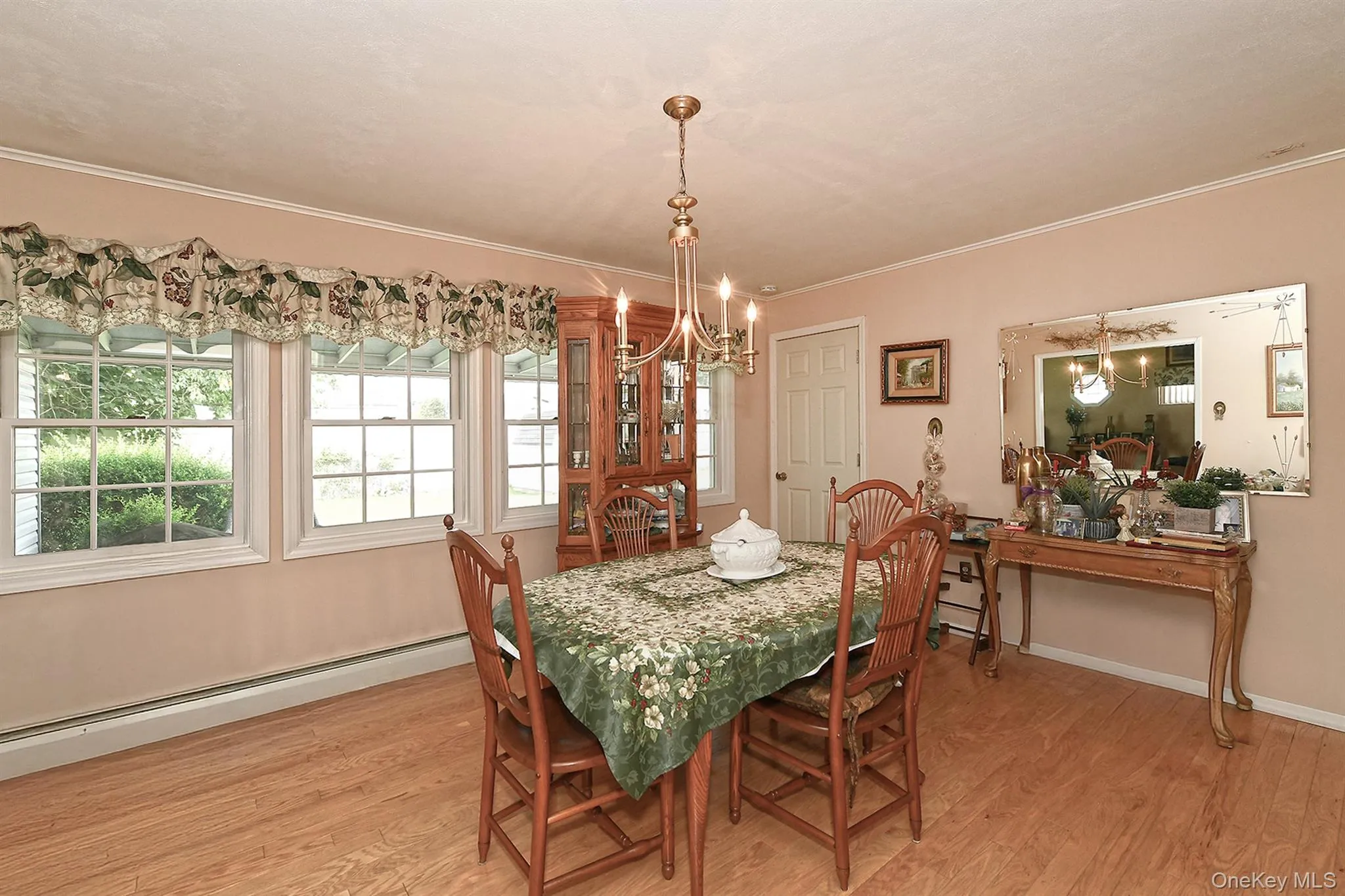 Light wood-finish flooring, three double-hung windows, crown molding, and a chandelier with candelabra bulbs Light wood-finish flooring, three double-hung windows, crown molding, and a chandelier with candelabra bulbs