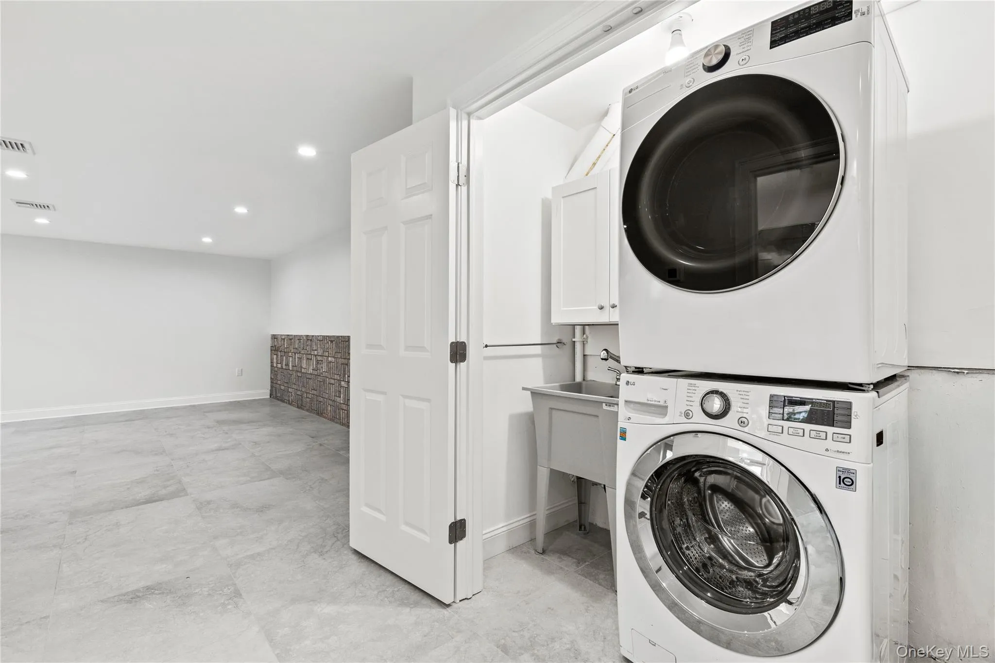 The Lower Level Laundry closet neatly contains a washer/dryer, a sink and additional room for cleaning products and extra storage. The Lower Level Laundry closet neatly contains a washer/dryer, a sink and additional room for cleaning products and extra storage.