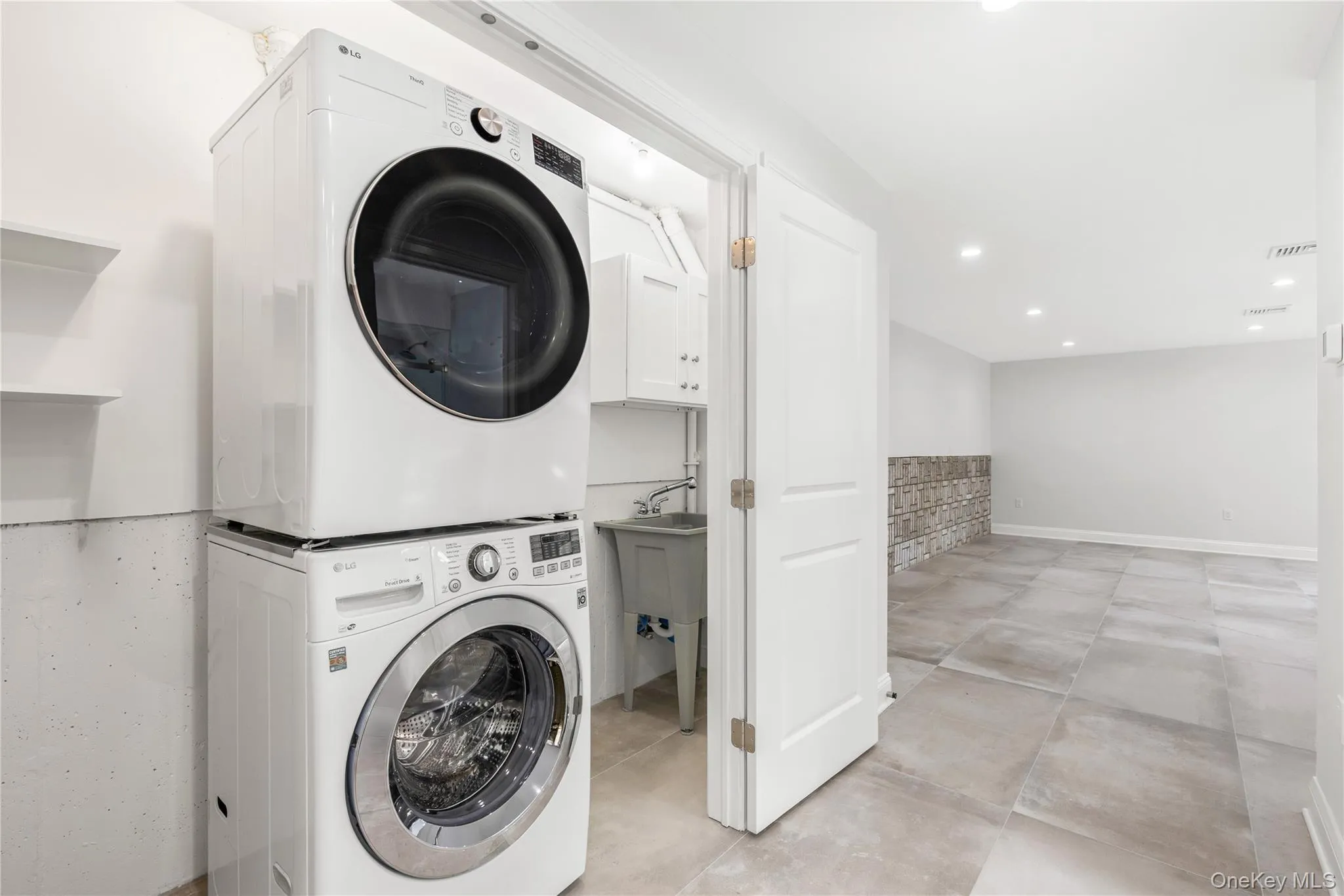 The Lower Level Laundry closet neatly contains a washer/dryer, a sink and additional room for cleaning products and extra storage. The Lower Level Laundry closet neatly contains a washer/dryer, a sink and additional room for cleaning products and extra storage.