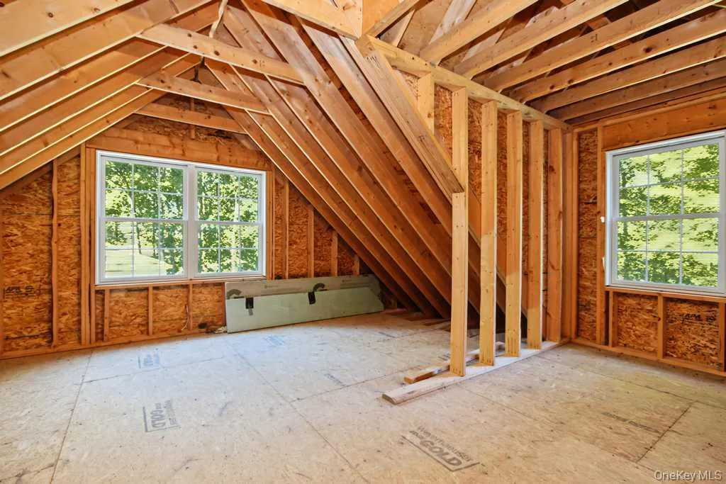 Unfinished attic space with exposed wood framing, two new windows, and oriented strand board flooring Unfinished attic space with exposed wood framing, two new windows, and oriented strand board flooring