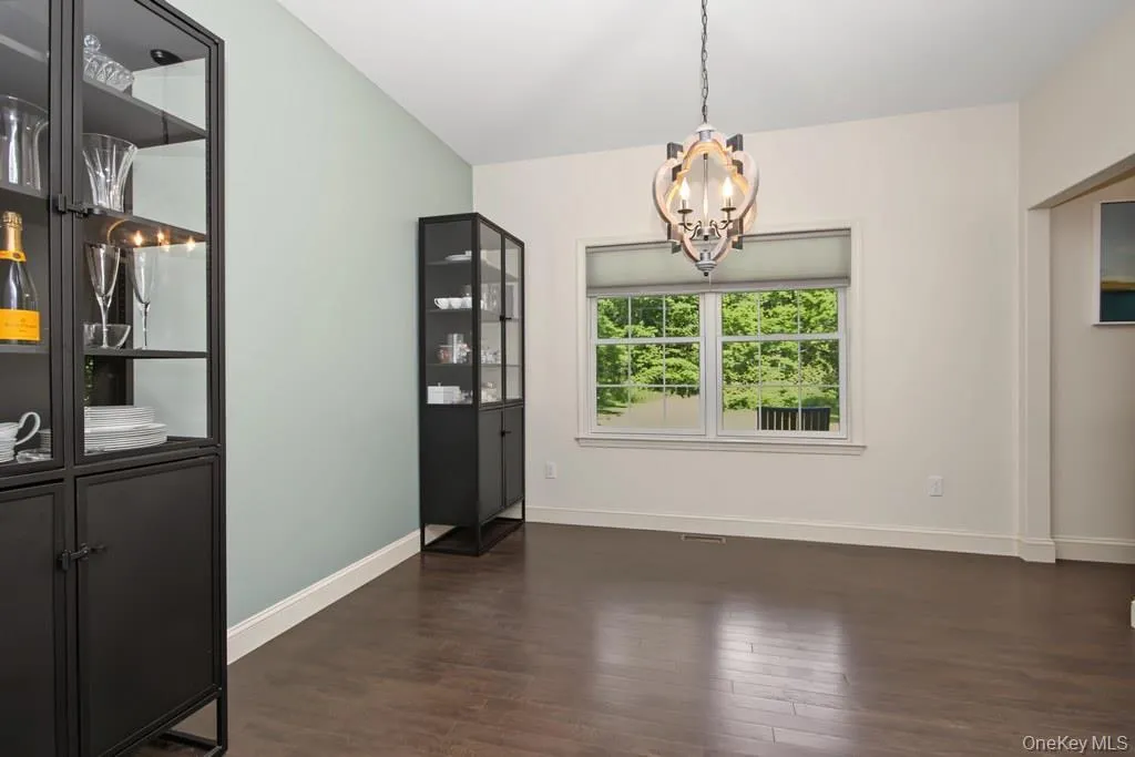 Dining room with vaulted ceiling with a chandelier, wood-finish flooring, and a large window with roller shades Dining room with vaulted ceiling with a chandelier, wood-finish flooring, and a large window with roller shades