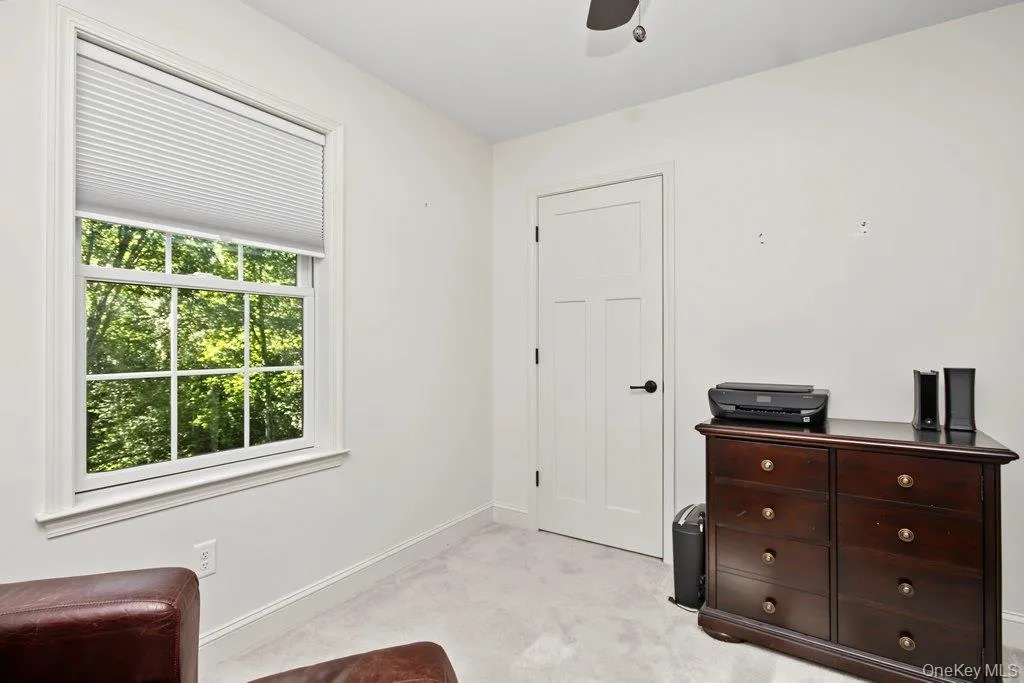 Double-hung window with white trim, white paneled door with black hardware, and light-colored carpeting Double-hung window with white trim, white paneled door with black hardware, and light-colored carpeting