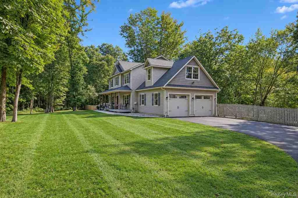 Two-story property featuring a covered porch, attached two-car garage, dormer windows, and a paved driveway Two-story property featuring a covered porch, attached two-car garage, dormer windows, and a paved driveway