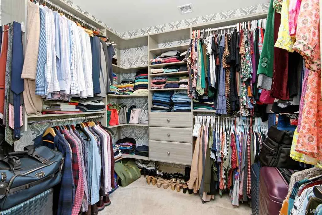 Custom closet system featuring multiple hanging rods, integrated shelving, and built-in drawers Custom closet system featuring multiple hanging rods, integrated shelving, and built-in drawers