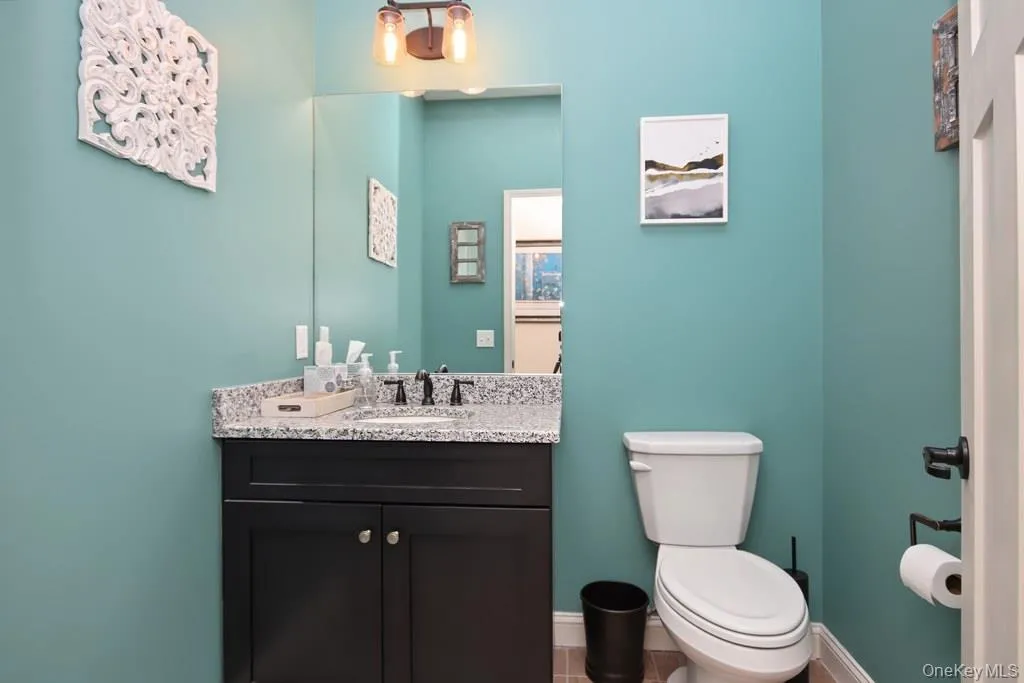 Bathroom featuring a dark wood-finish vanity with a light speckled countertop, dual-handle faucet, and a wall-mounted mirror Bathroom featuring a dark wood-finish vanity with a light speckled countertop, dual-handle faucet, and a wall-mounted mirror