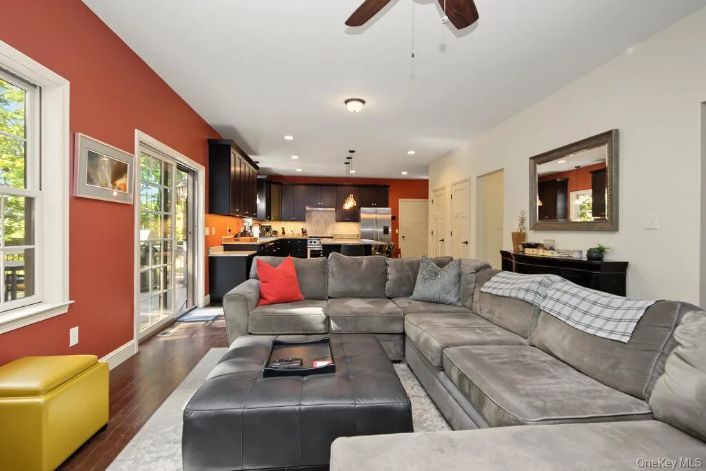 Recessed lighting and a ceiling fan illuminate a living area with wood-finish flooring Recessed lighting and a ceiling fan illuminate a living area with wood-finish flooring