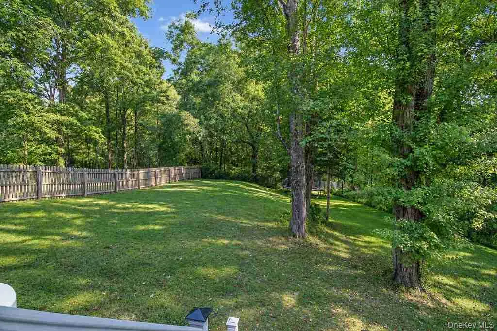 Expansive rear yard featuring a manicured lawn, established picket fencing, and mature trees Expansive rear yard featuring a manicured lawn, established picket fencing, and mature trees