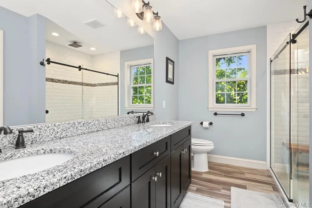 Dual vanity with speckled countertop and dark wood-finish cabinetry Dual vanity with speckled countertop and dark wood-finish cabinetry