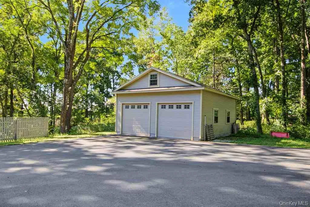 Detached two-car garage with electric and light-colored siding and a gable roof Detached two-car garage with electric and light-colored siding and a gable roof