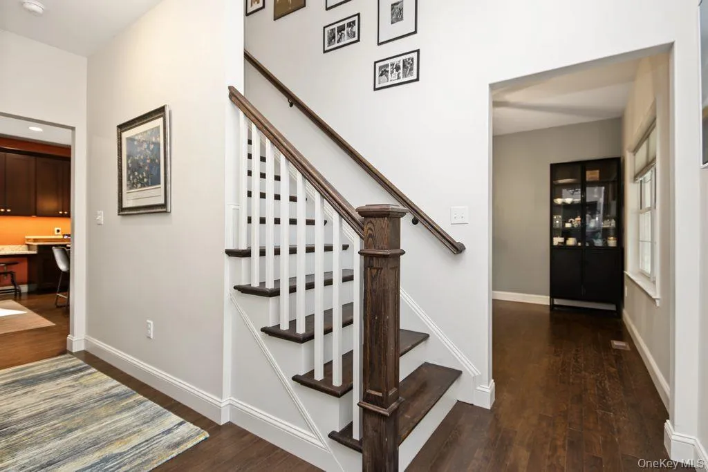 Hardwood flooring, painted white baseboards, traditional staircase with wood-finish handrail, and white risers Hardwood flooring, painted white baseboards, traditional staircase with wood-finish handrail, and white risers