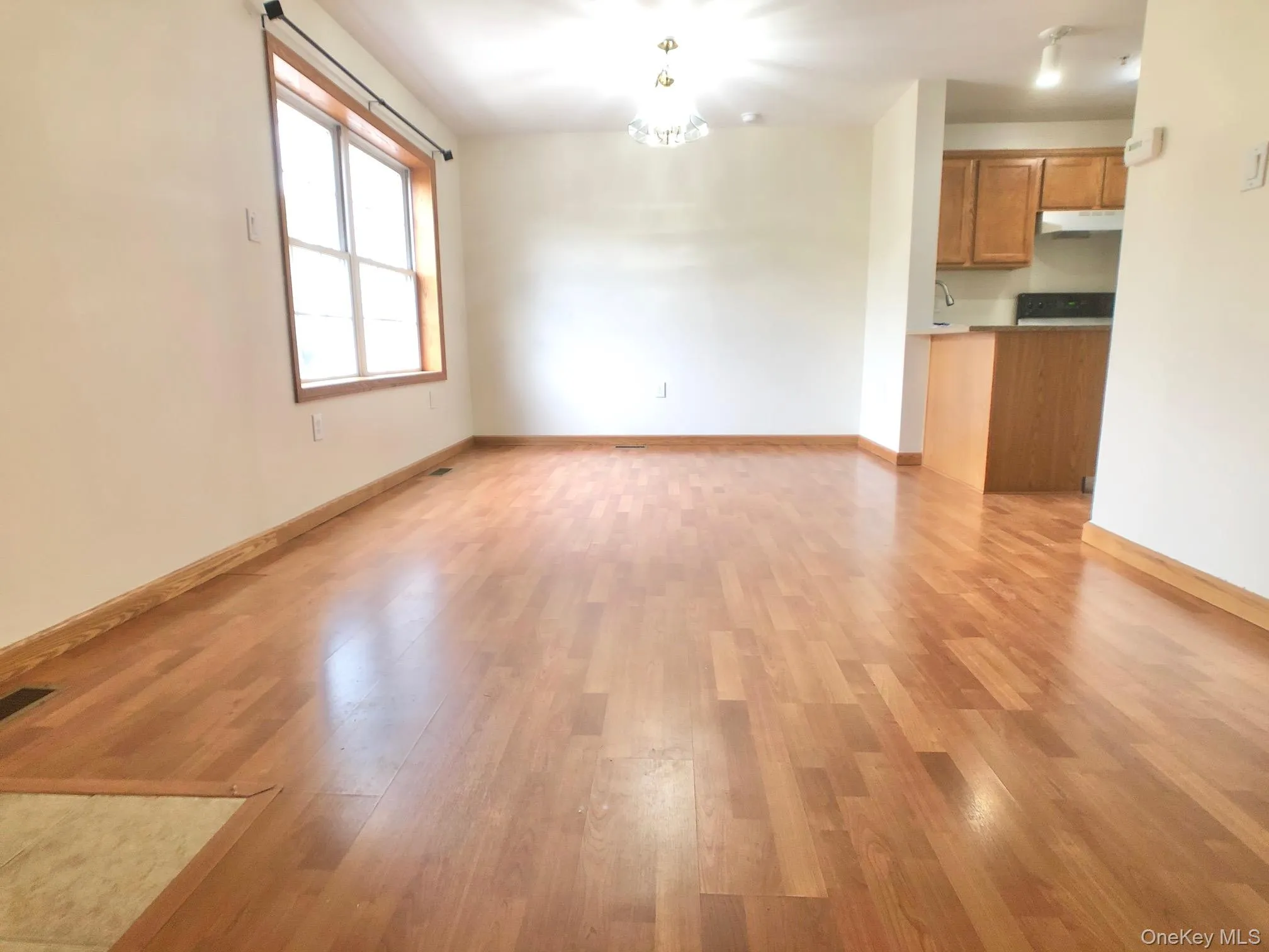 Unfurnished living room featuring a chandelier and light wood-style flooring Unfurnished living room featuring a chandelier and light wood-style flooring
