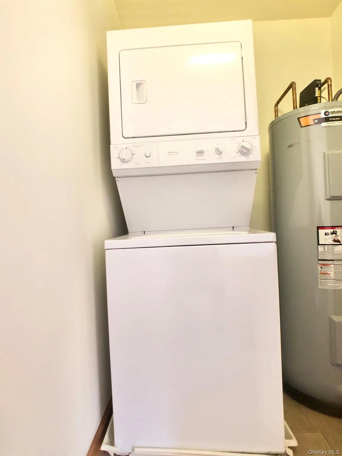 Laundry room featuring water heater and stacked washer / dryer Laundry room featuring water heater and stacked washer / dryer