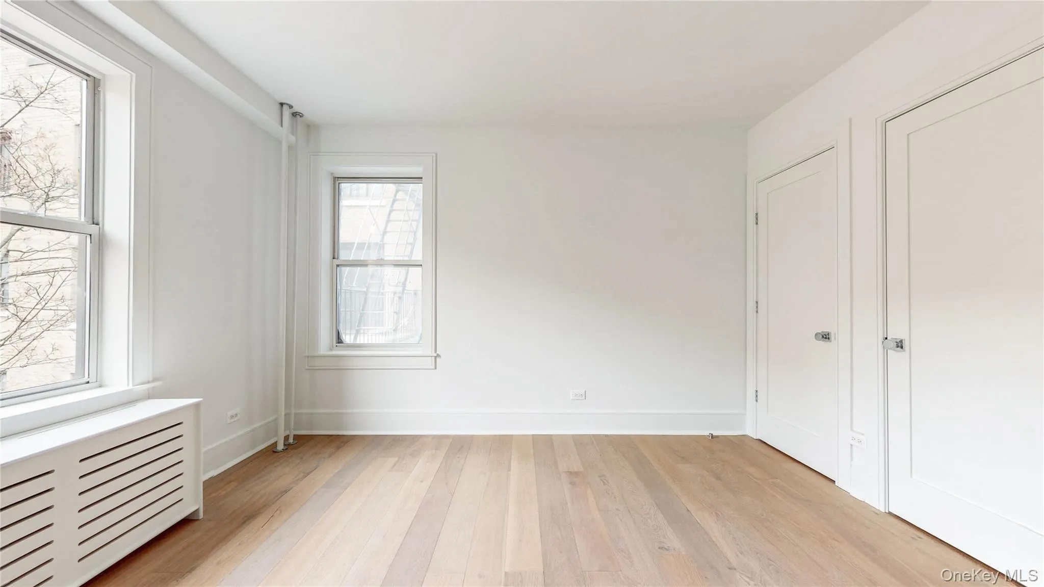 Light wood-finish flooring, white walls, two single-pane windows, and two white solid core doors Light wood-finish flooring, white walls, two single-pane windows, and two white solid core doors