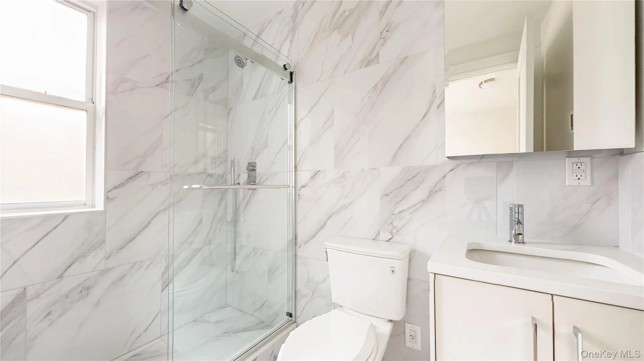 Shower with glass enclosure, white rectangular window, wall-mounted vanity with integrated sink, and mirrored medicine cabinet Shower with glass enclosure, white rectangular window, wall-mounted vanity with integrated sink, and mirrored medicine cabinet