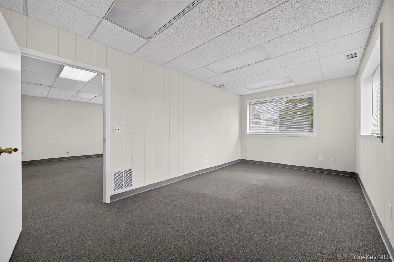 Textured carpet flooring, drop ceiling with integrated lighting, multiple windows Textured carpet flooring, drop ceiling with integrated lighting, multiple windows