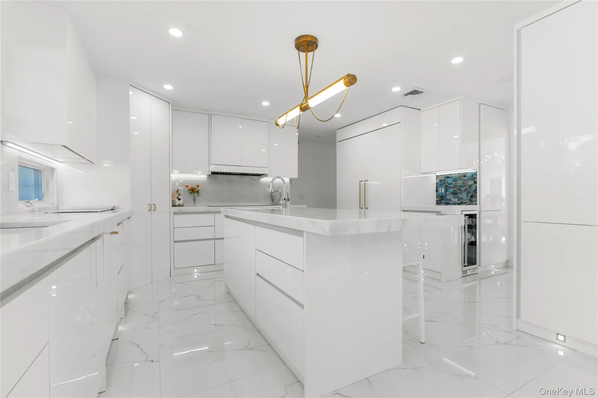 Kitchen with modern cabinets, white cabinetry, light marble finish flooring, light stone counters, and recessed lighting Kitchen with modern cabinets, white cabinetry, light marble finish flooring, light stone counters, and recessed lighting