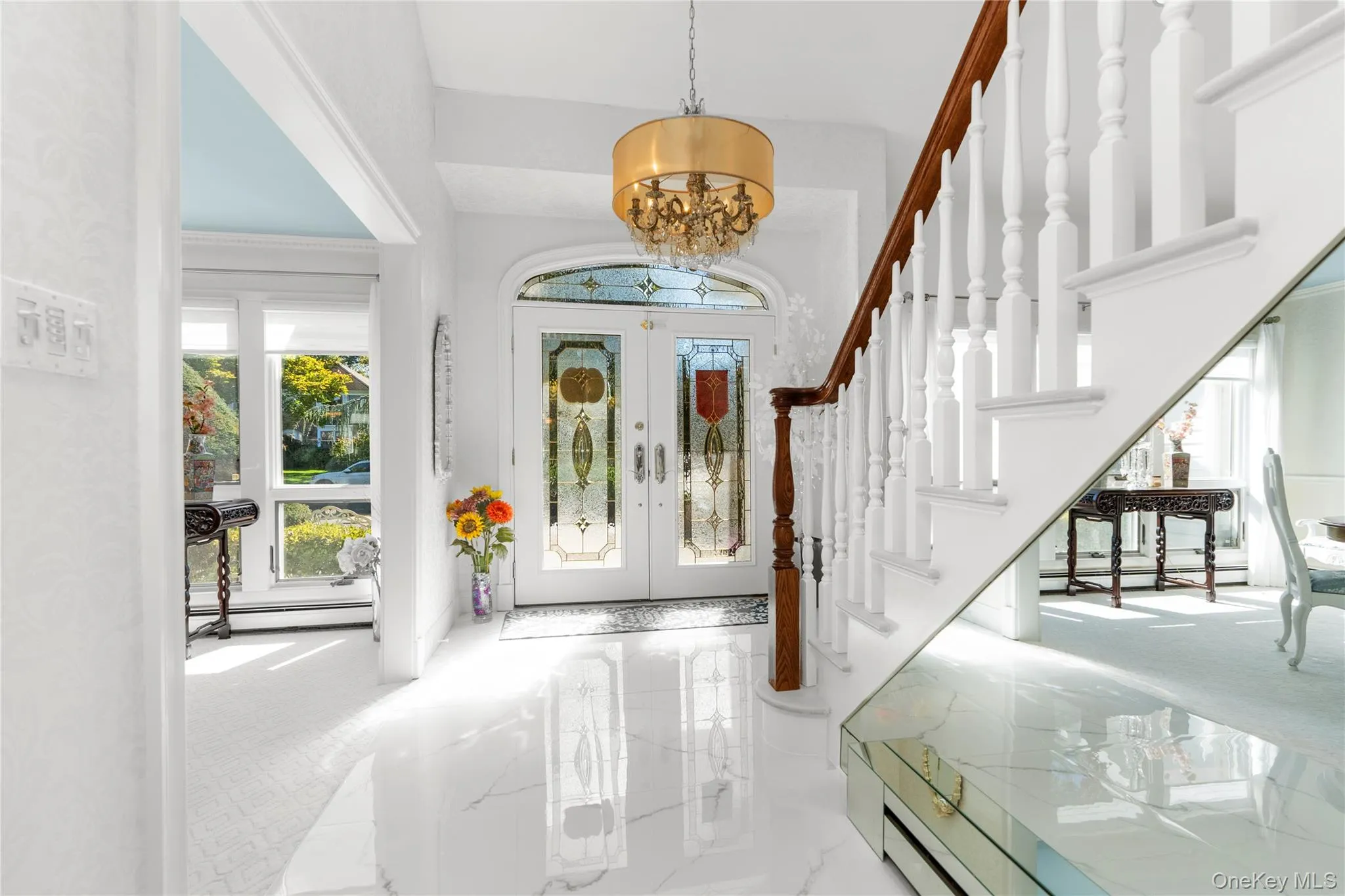 Foyer entrance featuring marble tiled flooring, a chandelier, french doors, stairway, and baseboard heating Foyer entrance featuring marble tiled flooring, a chandelier, french doors, stairway, and baseboard heating
