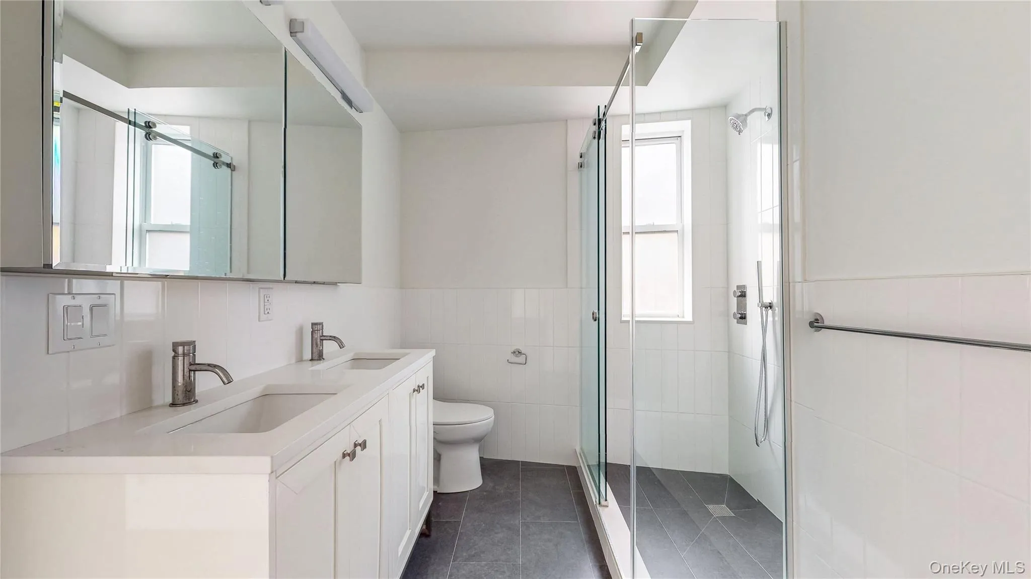 Dual vanity with undermount sinks, contemporary faucets, and white cabinetry Dual vanity with undermount sinks, contemporary faucets, and white cabinetry
