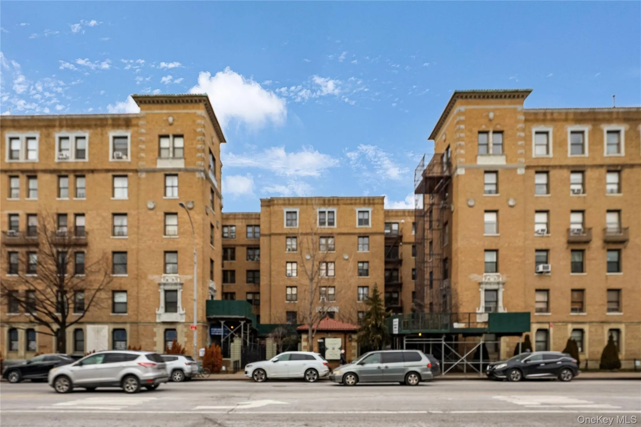 Multi-story building featuring a brick facade, multiple window styles, and a covered entrance Multi-story building featuring a brick facade, multiple window styles, and a covered entrance