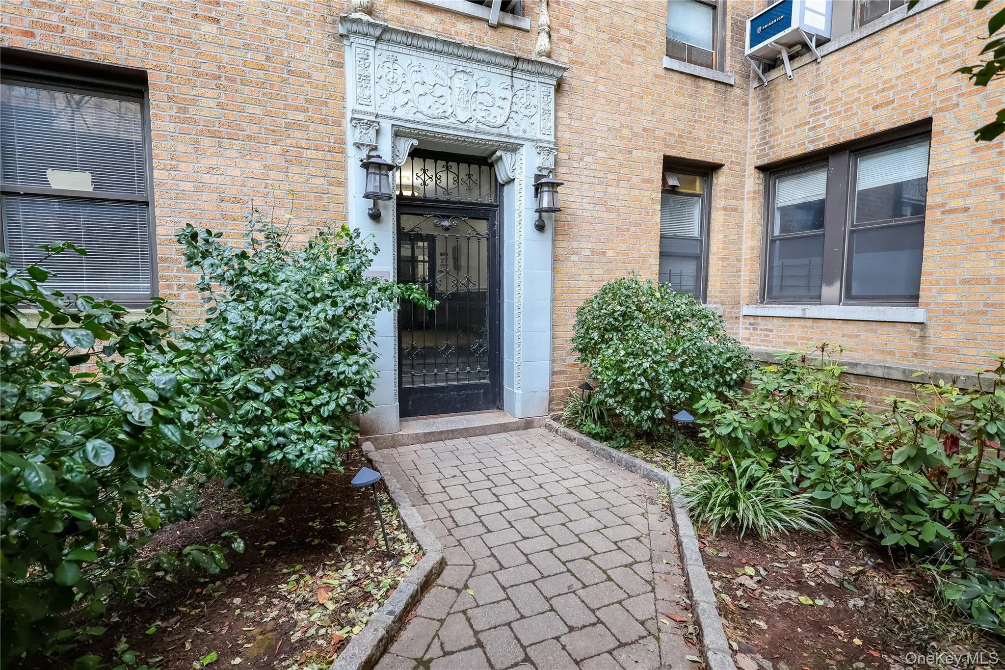 Brick exterior with decorative stone entryway, wrought iron entry door, and paver walkway Brick exterior with decorative stone entryway, wrought iron entry door, and paver walkway
