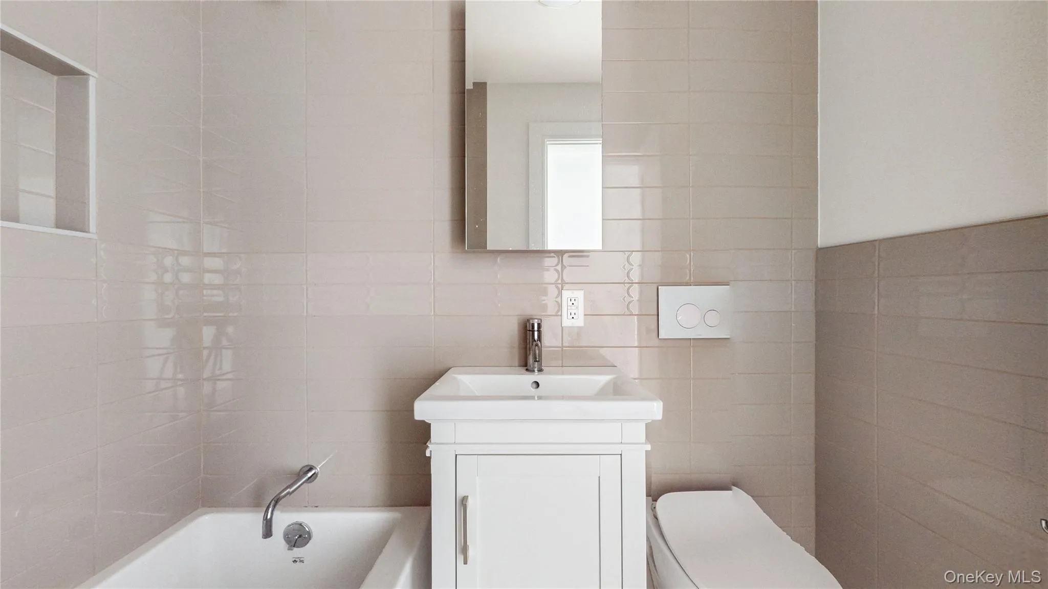 Full bathroom featuring a white vanity with integrated sink, chrome faucet, wall-mounted mirror, white bathtub with chrome fixtures, and a dual-flush toilet Full bathroom featuring a white vanity with integrated sink, chrome faucet, wall-mounted mirror, white bathtub with chrome fixtures, and a dual-flush toilet
