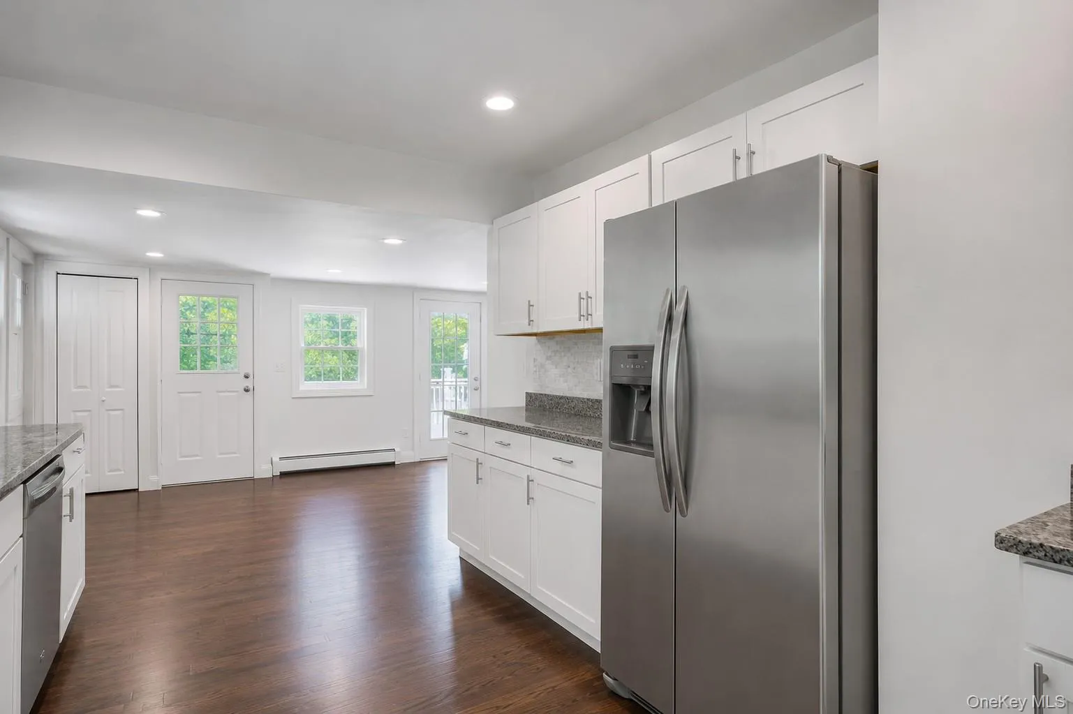 Kitchen featuring white cabinetry, stainless steel appliances, granite-style countertops, wood-finish flooring, and recessed lighting Kitchen featuring white cabinetry, stainless steel appliances, granite-style countertops, wood-finish flooring, and recessed lighting