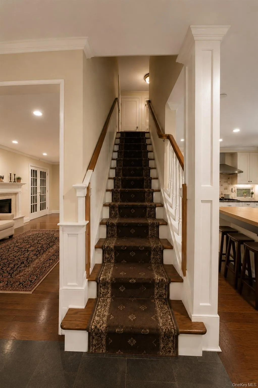 Elegant staircase featuring dark wood treads with coordinating patterned runner, white painted newels and balusters, and warm wood handrails Elegant staircase featuring dark wood treads with coordinating patterned runner, white painted newels and balusters, and warm wood handrails