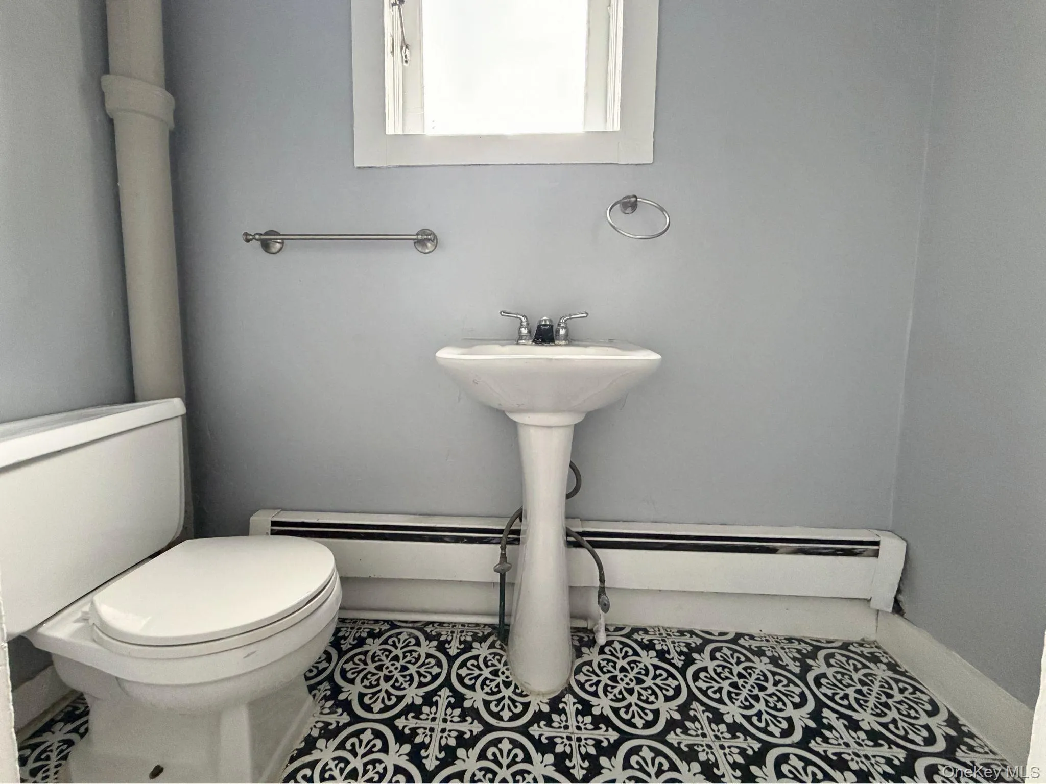 Second Level 1/2 bath, Pedestal sink, toilet, mosaic tile flooring, and wall-mounted towel bar Second Level 1/2 bath, Pedestal sink, toilet, mosaic tile flooring, and wall-mounted towel bar