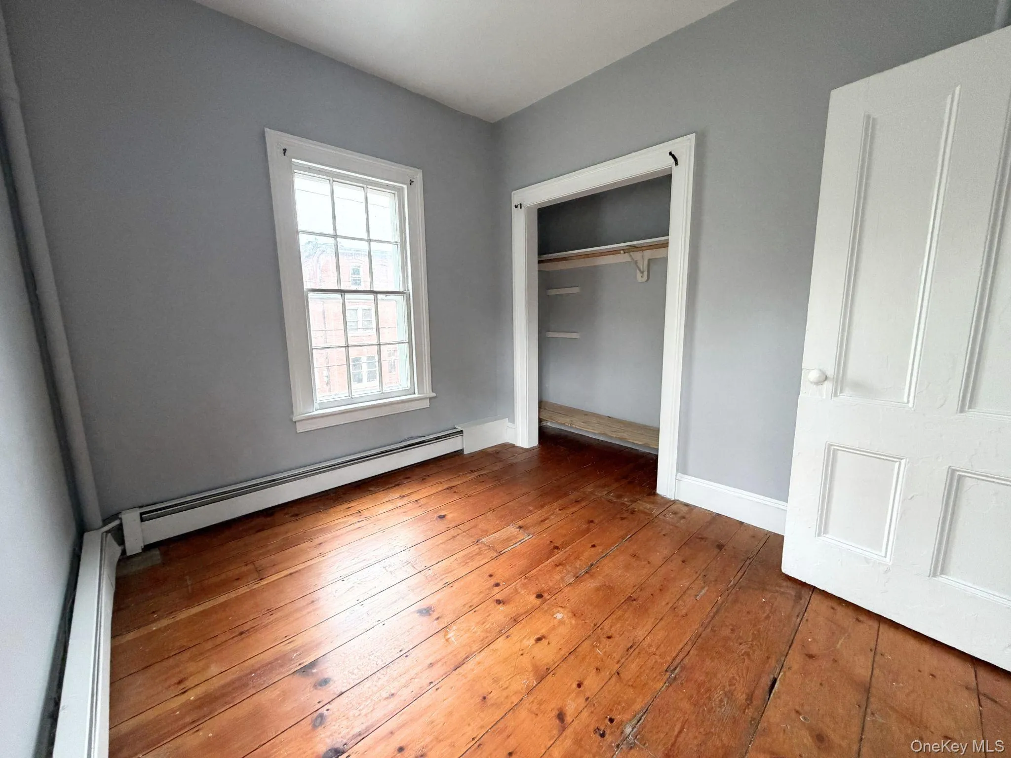 Wood-finish flooring, white trim, and a window with natural light Wood-finish flooring, white trim, and a window with natural light