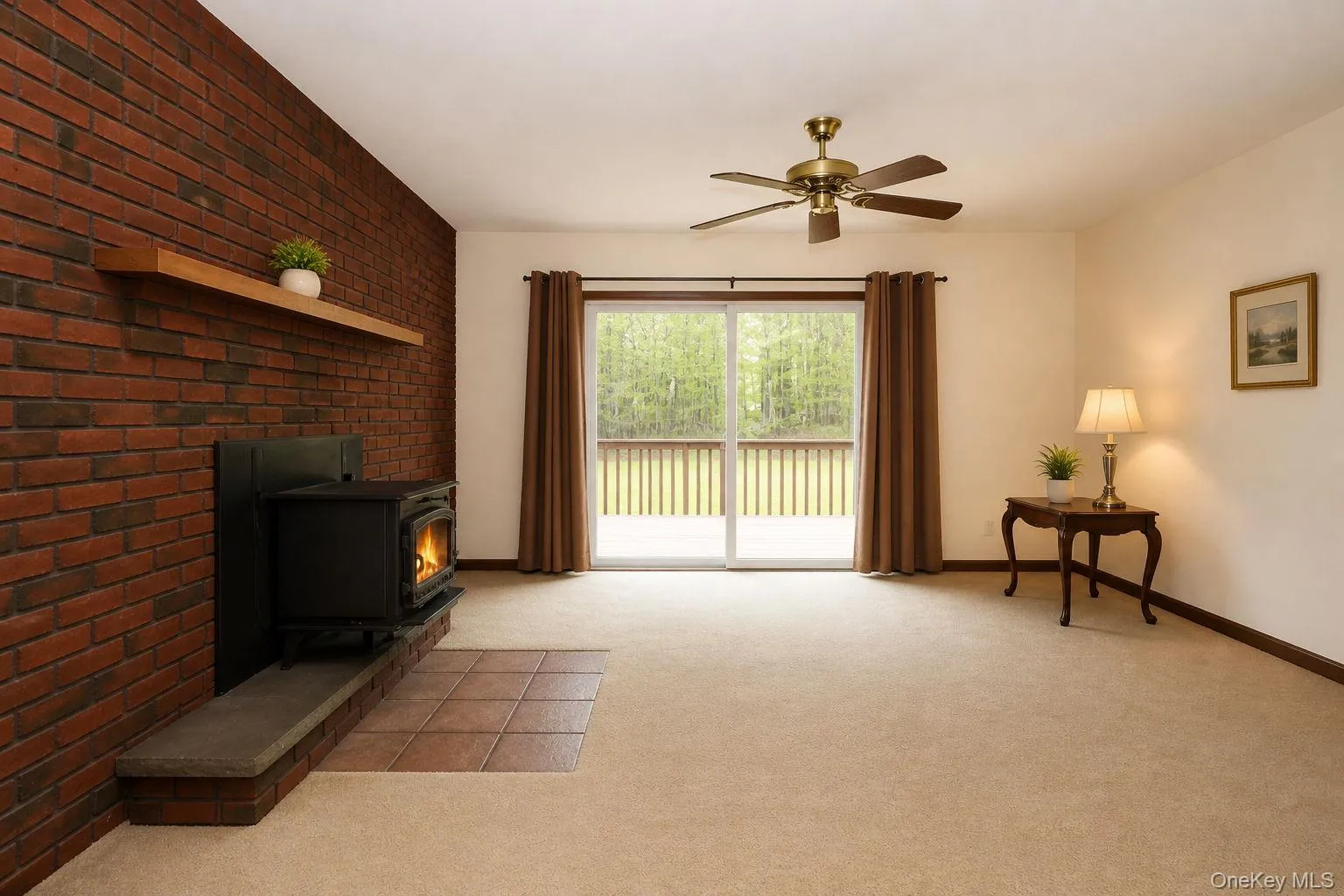Open living space featuring a brick accent wall with a floating wood shelf Open living space featuring a brick accent wall with a floating wood shelf