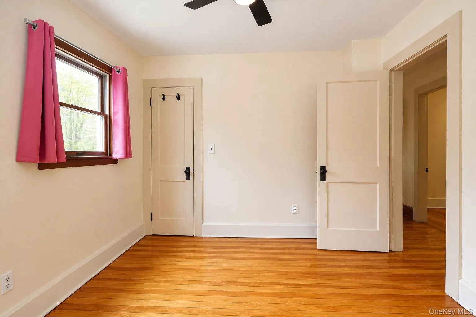 Bright interior space featuring wood-finish flooring, a ceiling fan, and a double-hung window with wood trim Bright interior space featuring wood-finish flooring, a ceiling fan, and a double-hung window with wood trim