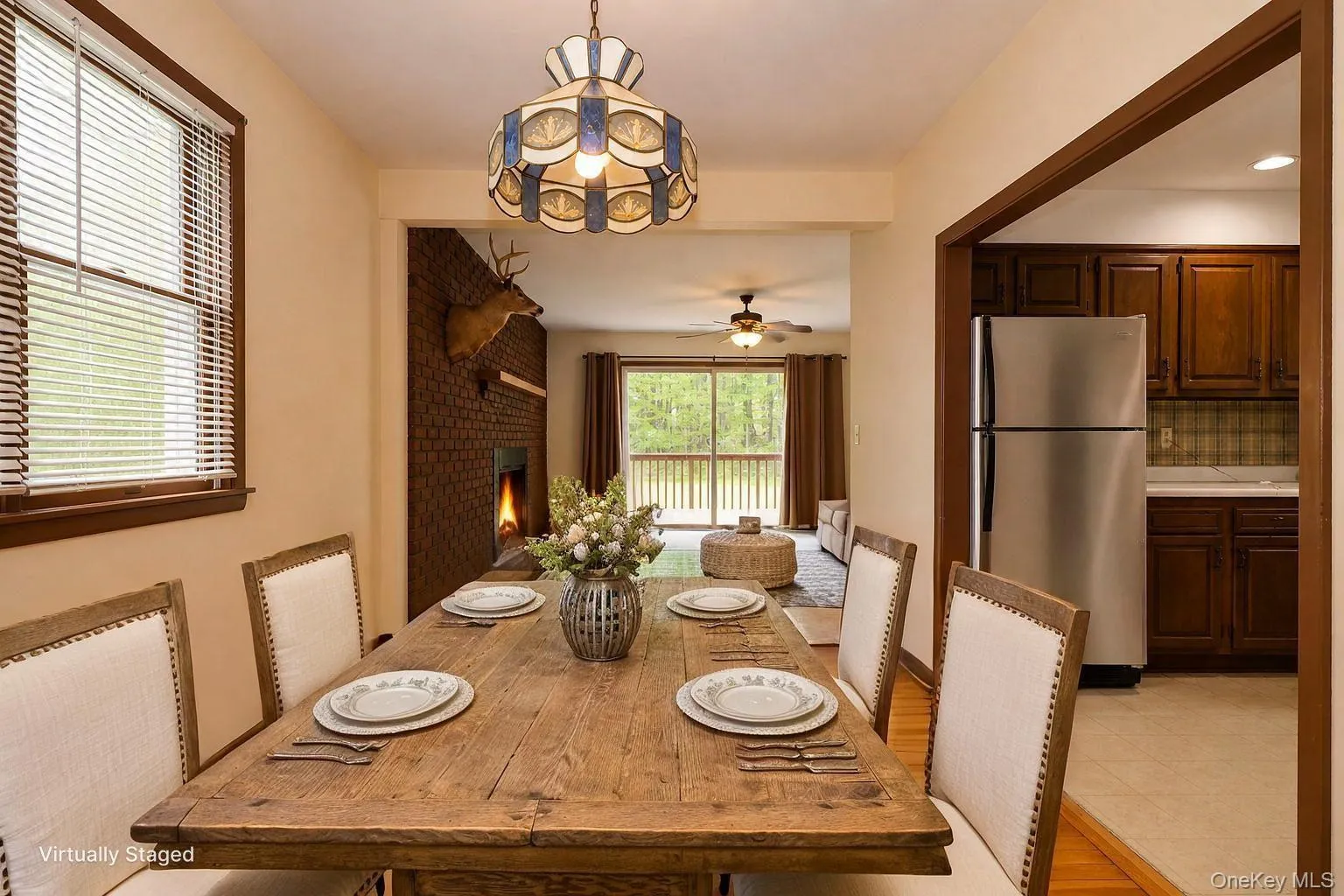 Dining area featuring a rustic wood-finish table, a stained-glass pendant light fixture, and a window with blinds Dining area featuring a rustic wood-finish table, a stained-glass pendant light fixture, and a window with blinds
