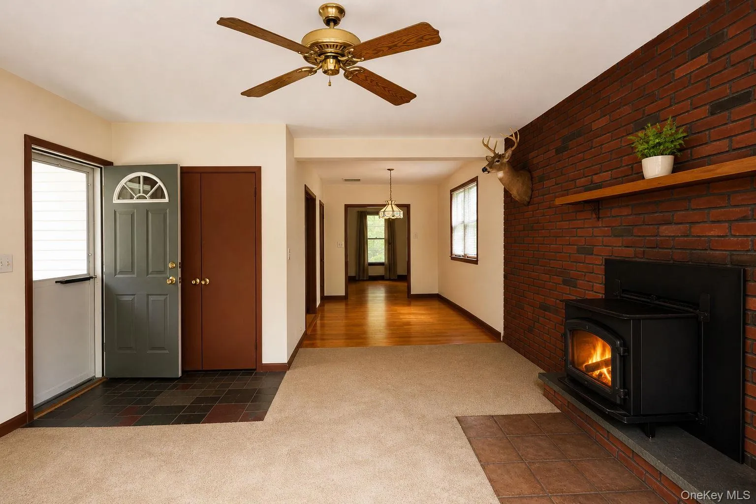 Living area featuring a brick accent wall with a wood-burning stove on a tiled hearth Living area featuring a brick accent wall with a wood-burning stove on a tiled hearth
