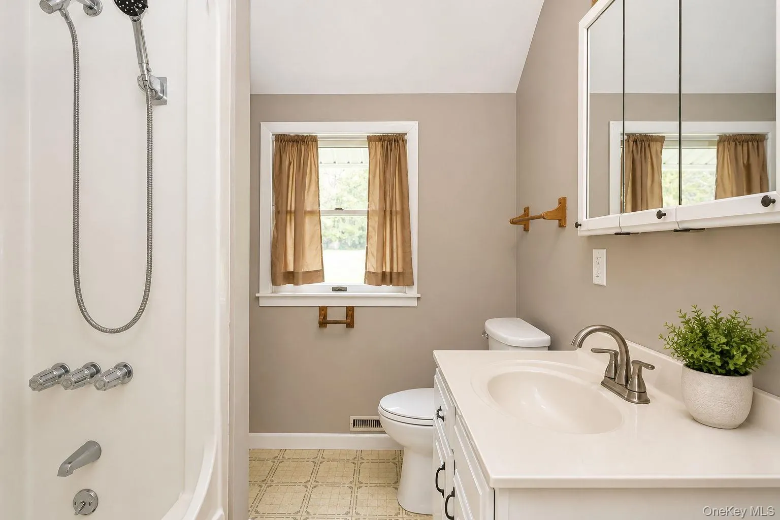 Bathroom vanity featuring a white countertop with integrated sink, brushed nickel faucet, and a wall-mounted mirrored medicine cabinet Bathroom vanity featuring a white countertop with integrated sink, brushed nickel faucet, and a wall-mounted mirrored medicine cabinet