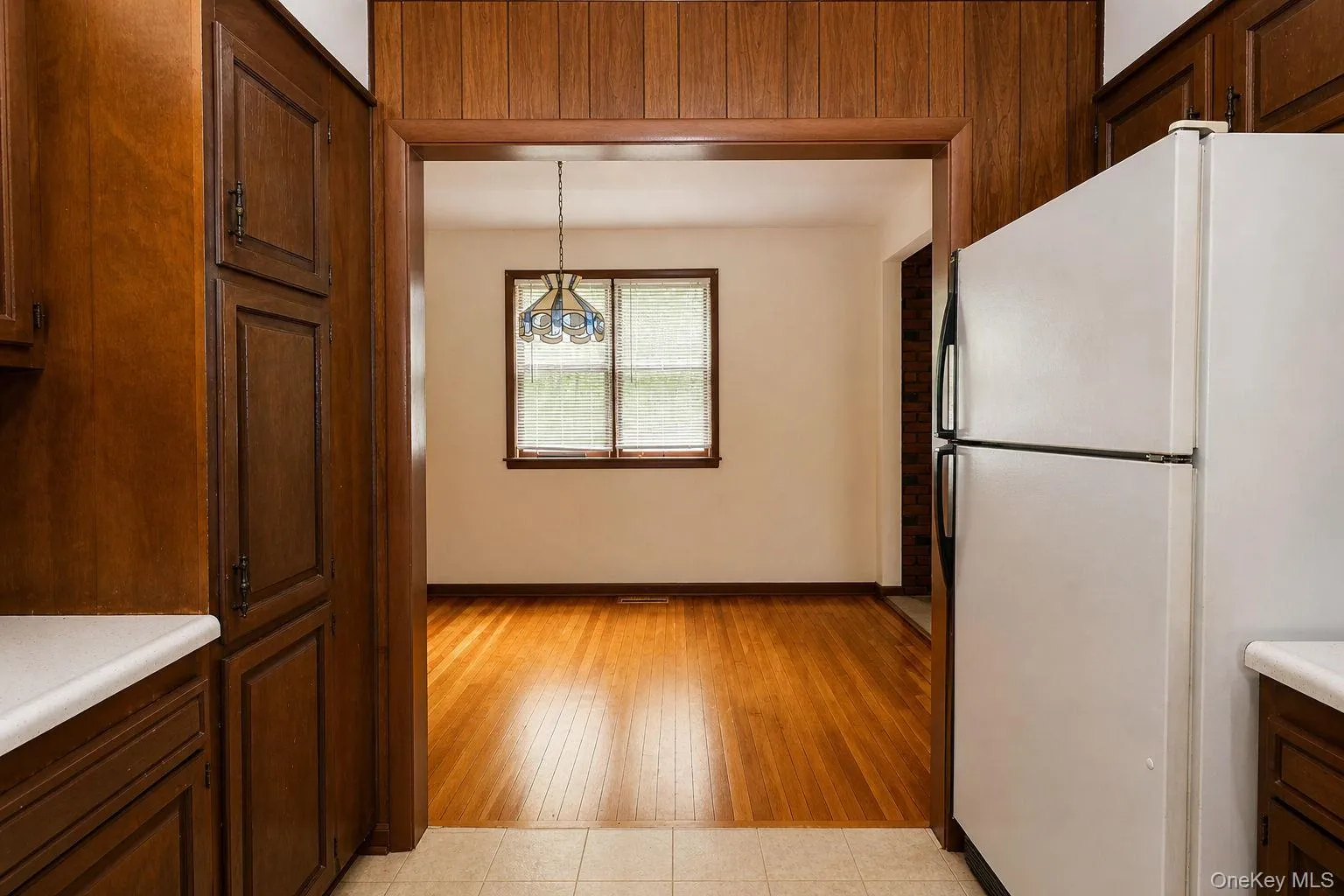 Kitchen area featuring wood-finish cabinetry, white countertops, and a white refrigerator Kitchen area featuring wood-finish cabinetry, white countertops, and a white refrigerator