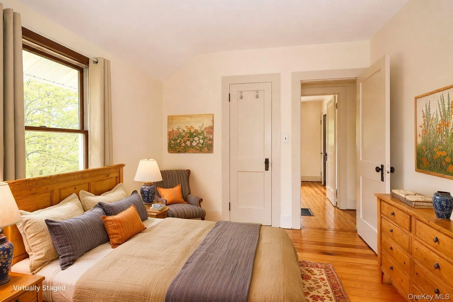 Light-filled room featuring wood-finish flooring, a single window with wood framing, and multiple panel doors with dark hardware Light-filled room featuring wood-finish flooring, a single window with wood framing, and multiple panel doors with dark hardware