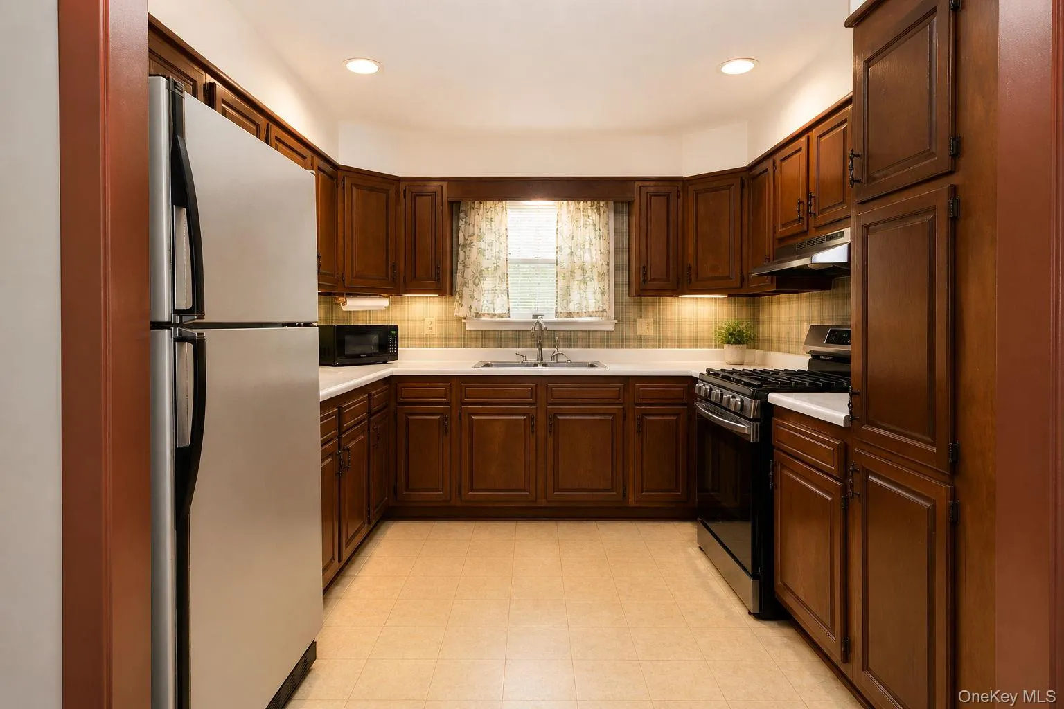 U-shaped kitchen with wood-finish cabinetry, white countertops, and a tiled backsplash U-shaped kitchen with wood-finish cabinetry, white countertops, and a tiled backsplash