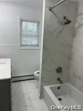 Bathtub with subway tile surround, wall-mounted shower head, and brushed nickel fixtures Bathtub with subway tile surround, wall-mounted shower head, and brushed nickel fixtures