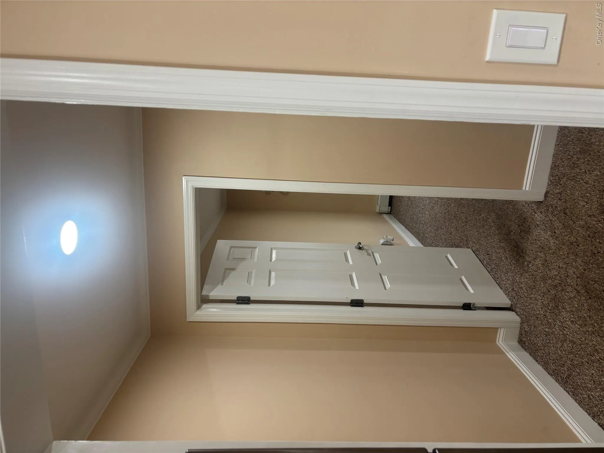 Recessed ceiling lighting, textured wall-to-wall carpeting, crown molding, six-panel interior door, and a wall-mounted light switch Recessed ceiling lighting, textured wall-to-wall carpeting, crown molding, six-panel interior door, and a wall-mounted light switch